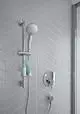 Brausekombination von Ideal Standard mit einem verstellbaren Handbrausehalter und zwei Pflegeprodukten in einer Wandablage, montiert an einer gefliesten Wand in hellen Tönen.
